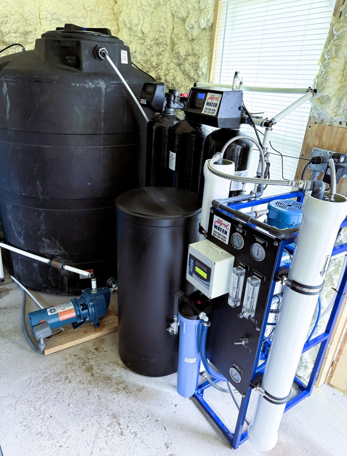 Commercial reverse osmosis skid with storage tank and pump.